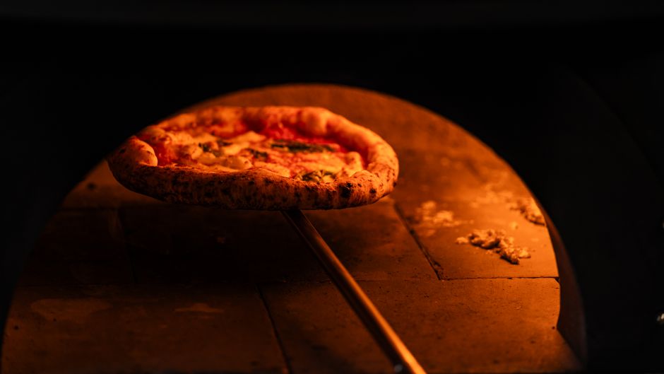 Neapolitan pizza with melted mozzarella and fresh basil straight from a wood-fired oven